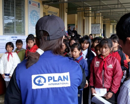 Photo d'une bénévole de plan international parlant a des enfants
